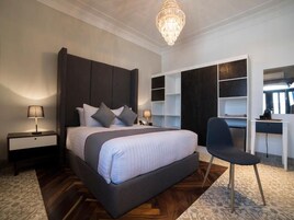Een moderne slaapkamer met een groot bed, nachtkastjes, een bureau en ingebouwde kasten.