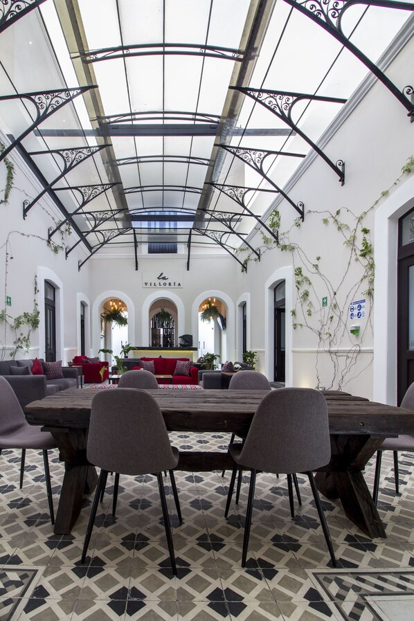 A spacious indoor dining area with a high ceiling, a central bar, and a patterned floor.