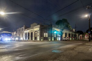 Una escena nocturna en la calle con un edificio que presenta un gran arco y un letrero que dice 'Hotel de France'.