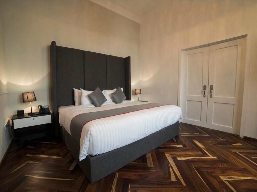 Un dormitorio con una cama grande, dos mesitas de noche, un armario y un suelo con estampado de espiga.