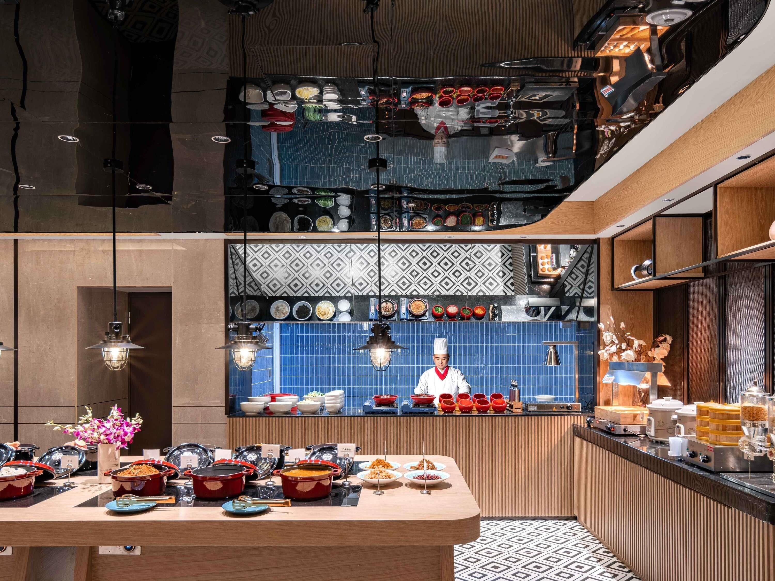 Una cocina moderna con un chef preparando comida, una variedad de platos expuestos y una distribución limpia y ordenada.