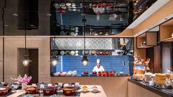 Una cocina moderna con un chef preparando comida, una variedad de platos expuestos y una distribución limpia y ordenada.
