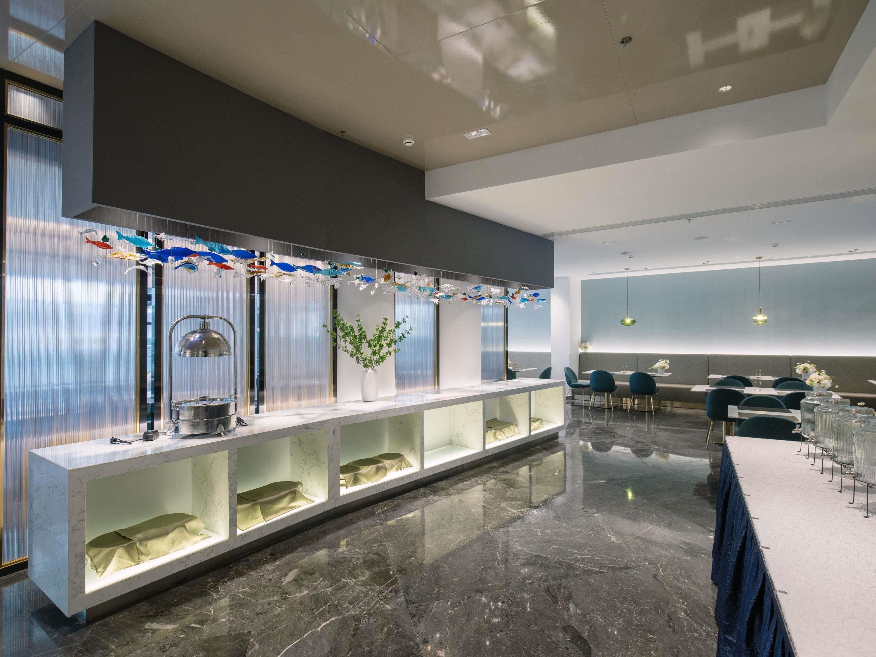 Un moderno vestíbulo de hotel con un mostrador de recepción de mármol, zona de estar y ornamentos decorativos con forma de peces.