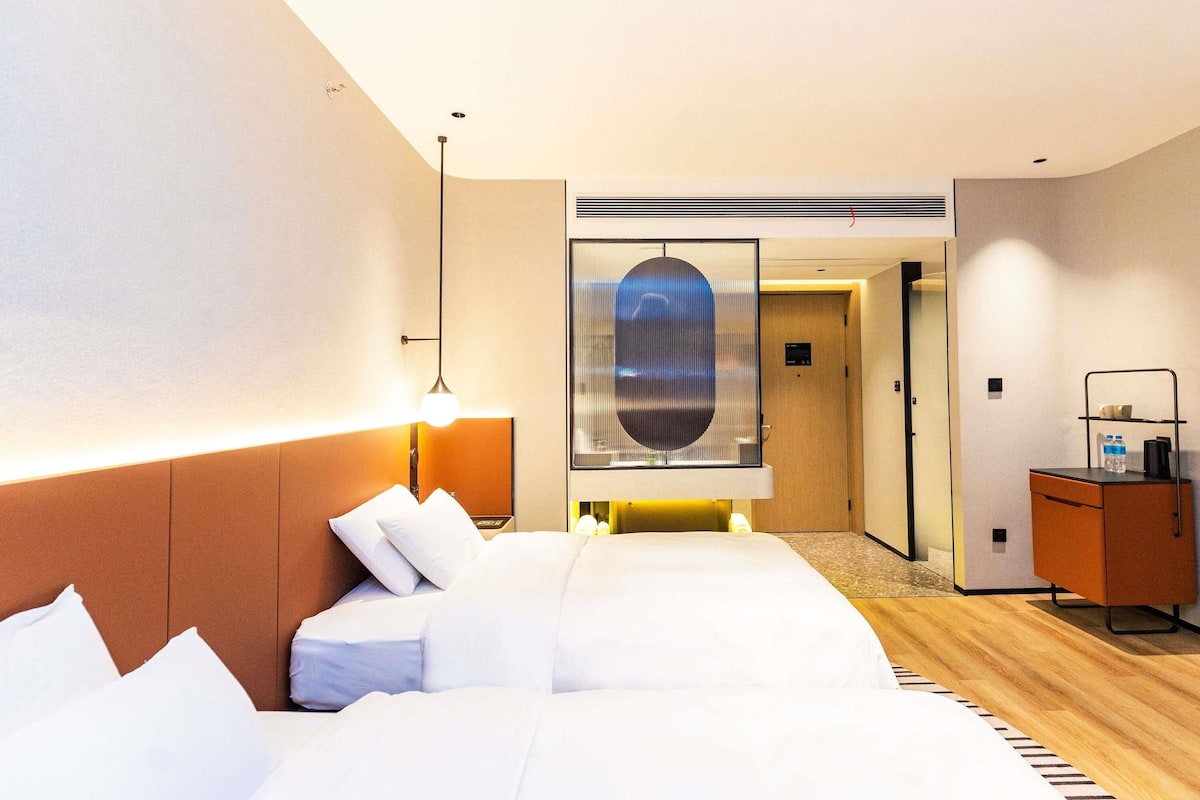 Ein Hotelzimmer mit Bett, Nachttischlampe und Blick auf den Flur.