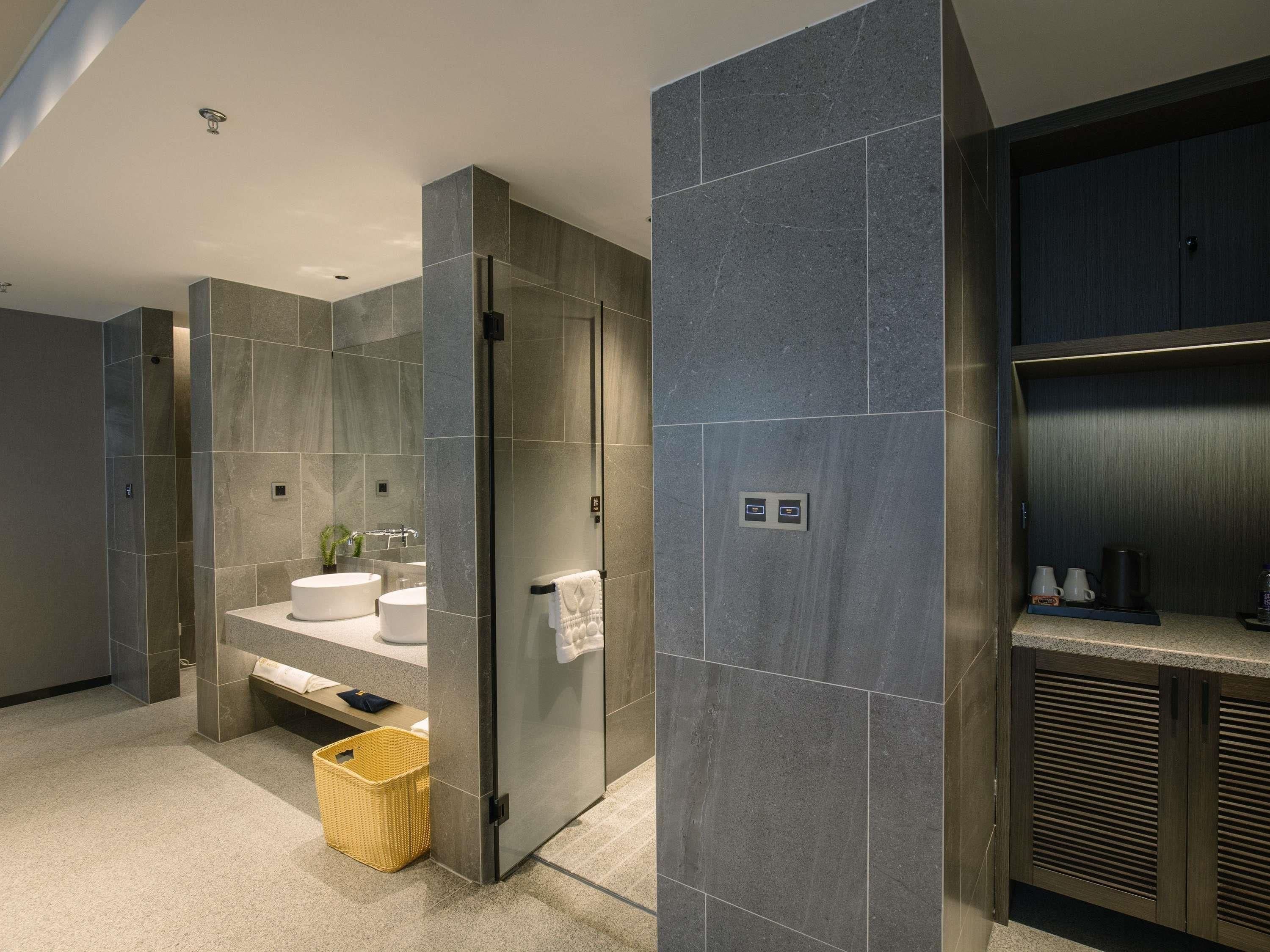 A modern bathroom with a glass shower enclosure, a white sink, and a towel rack.