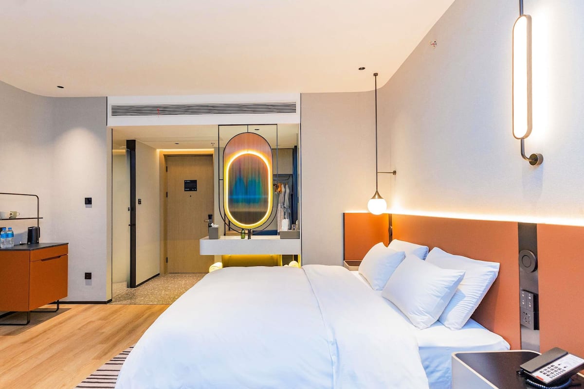 Ein Hotelzimmer mit einem Bett, einem Nachttisch und einem Spiegel.