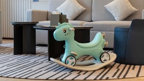 A teal rocking horse toy on a patterned rug, a grey sofa with white cushions, and a black side table with a tissue box. - Novotel Nantong Center (Nantong)