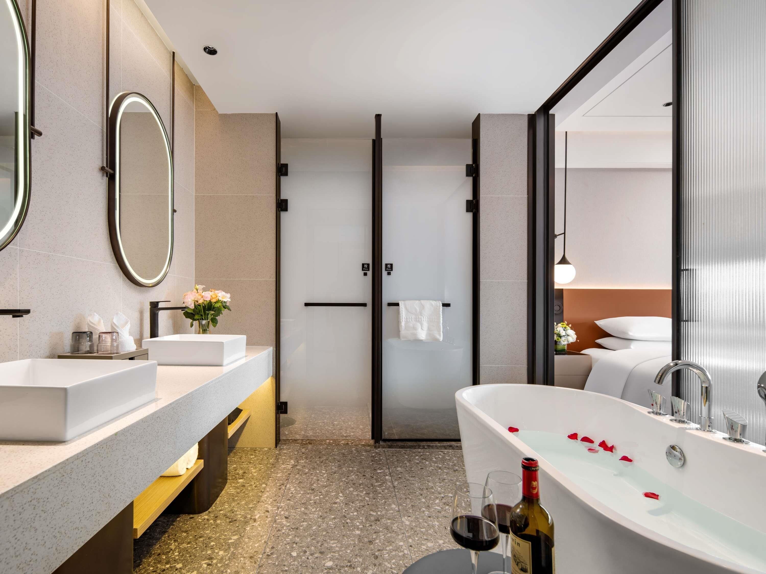 Un baño moderno con una bañera independiente, un espejo grande y un tocador con encimera.