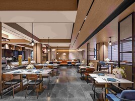 Un restaurante amplio con varias áreas de comedor, una zona de estar central y una cocina visible a la izquierda.