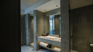 A modern bathroom with a large mirror, a sink, and a shower area. - Novotel Nantong Center (Nantong)