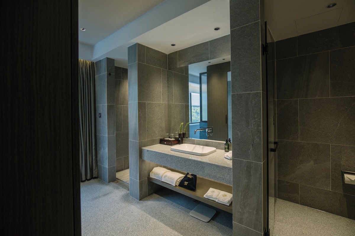 A modern bathroom with a large mirror, a sink, and a shower area.