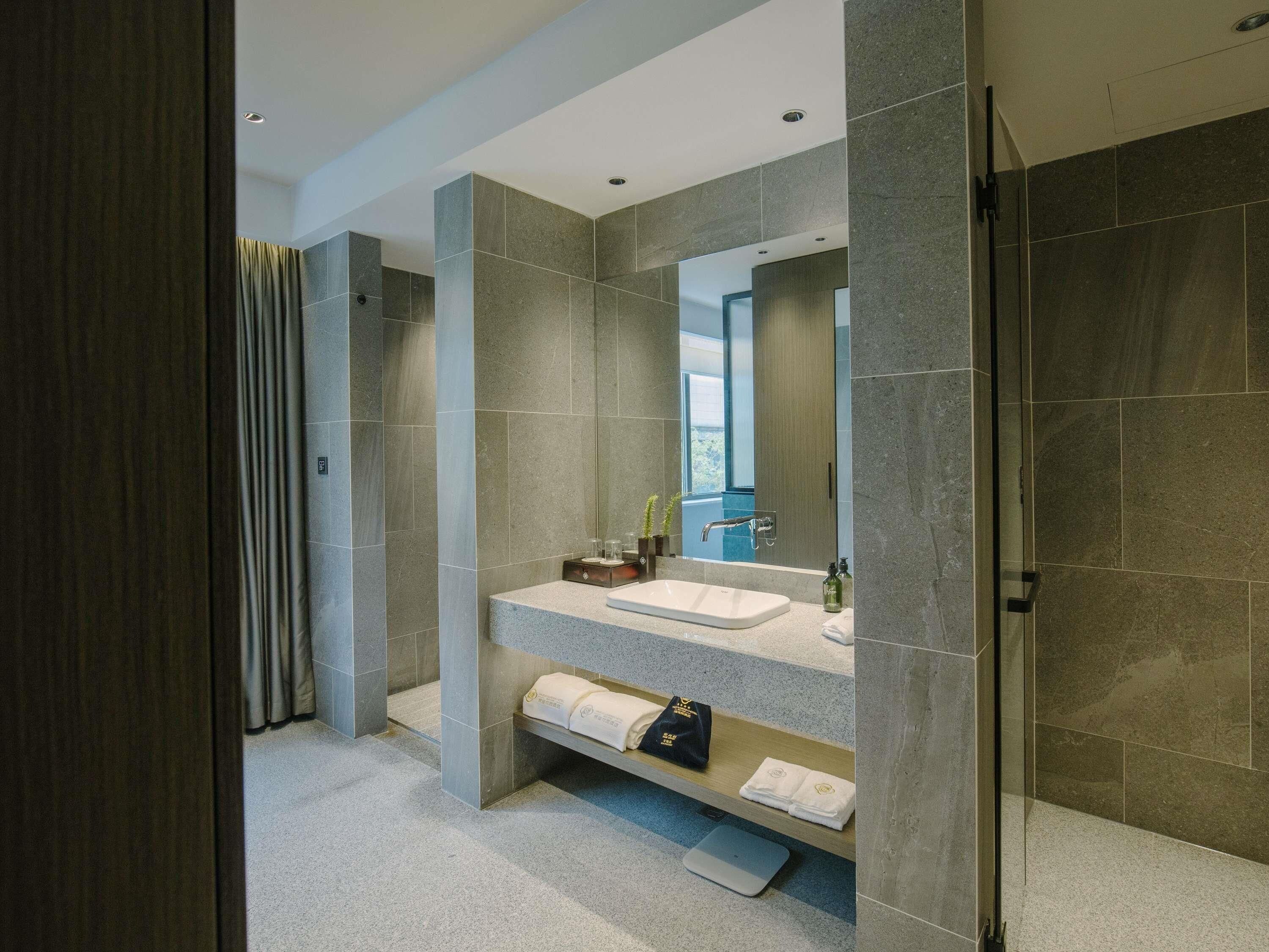 Un baño moderno con un espejo grande, un lavabo y una zona de ducha.