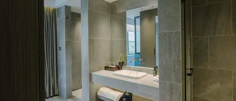Un baño moderno con un espejo grande, un lavabo y una zona de ducha.