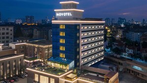 A high-rise hotel with a prominent 'NOVOTEL' sign, multiple floors, and a rooftop garden. - Novotel Nantong Center (Nantong)