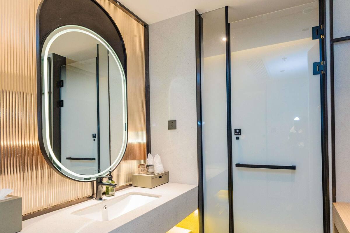 Ein modernes Badezimmer mit einem großen Spiegel, einem Waschbecken und einer Duschkabine aus Glas.