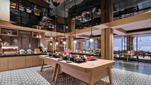 A modern restaurant with a central wooden table, hanging lights, and patterned floor tiles. - Novotel Nantong Center (Nantong)