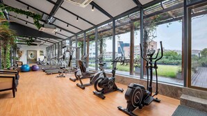 A gym with exercise equipment, large windows, and a wooden floor. - Novotel Nantong Center (Nantong)