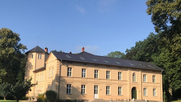 Un grand bâtiment à deux étages, doté d’une façade symétrique, de nombreuses fenêtres et d’une entrée centrale.