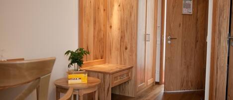 A wooden interior with a dining table, chairs, a small plant, and a cabinet.