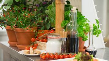 Una encimera de cocina con diversos ingredientes y utensilios, como tomates, hierbas y botellas.