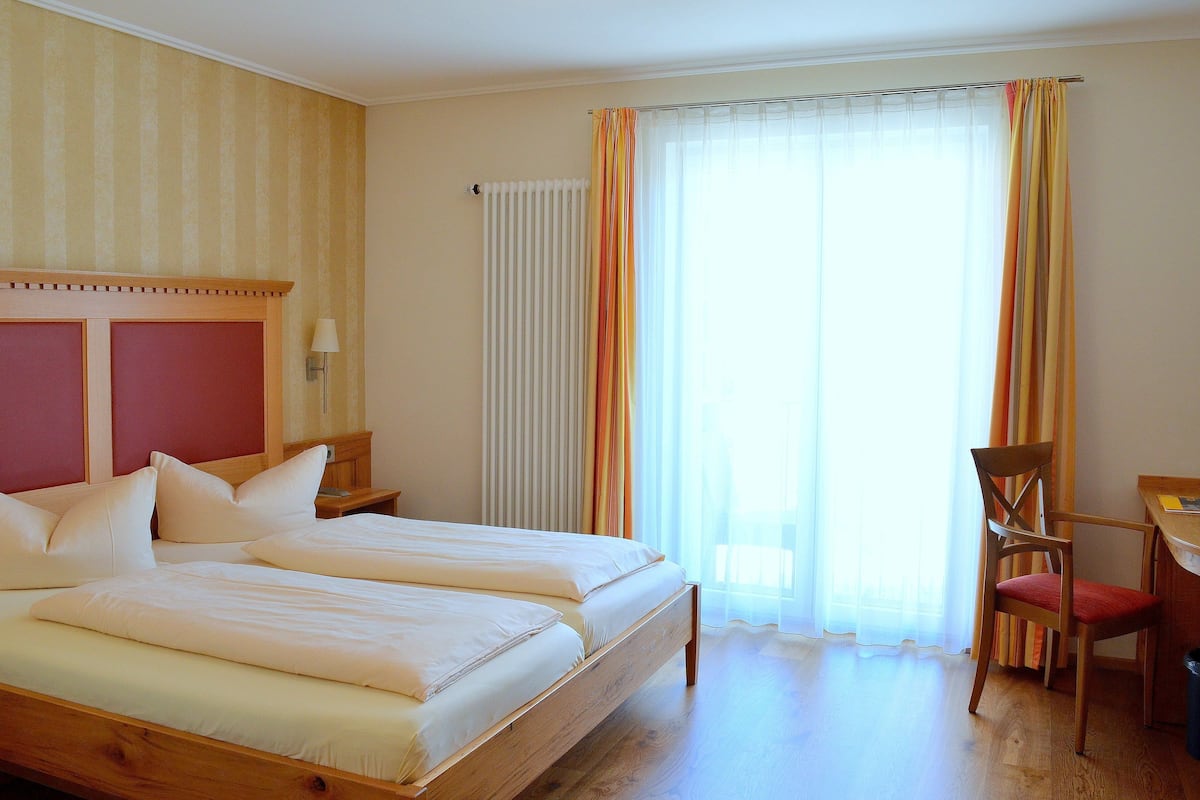 A hotel room with two beds, a desk, and a chair.