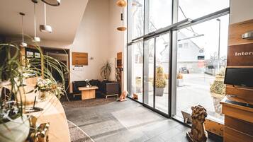 A modern reception area with a large glass door, a reception desk, and a seating area with a sofa and chairs.