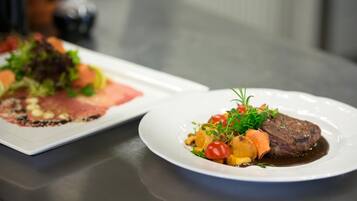 Uma mesa de jantar com dois pratos de comida, um com bife e legumes, e outro com um prato diferente.