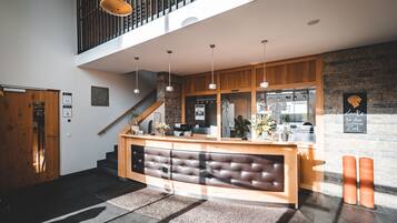 A modern reception area with a wooden reception desk, a staircase, and a stone wall.