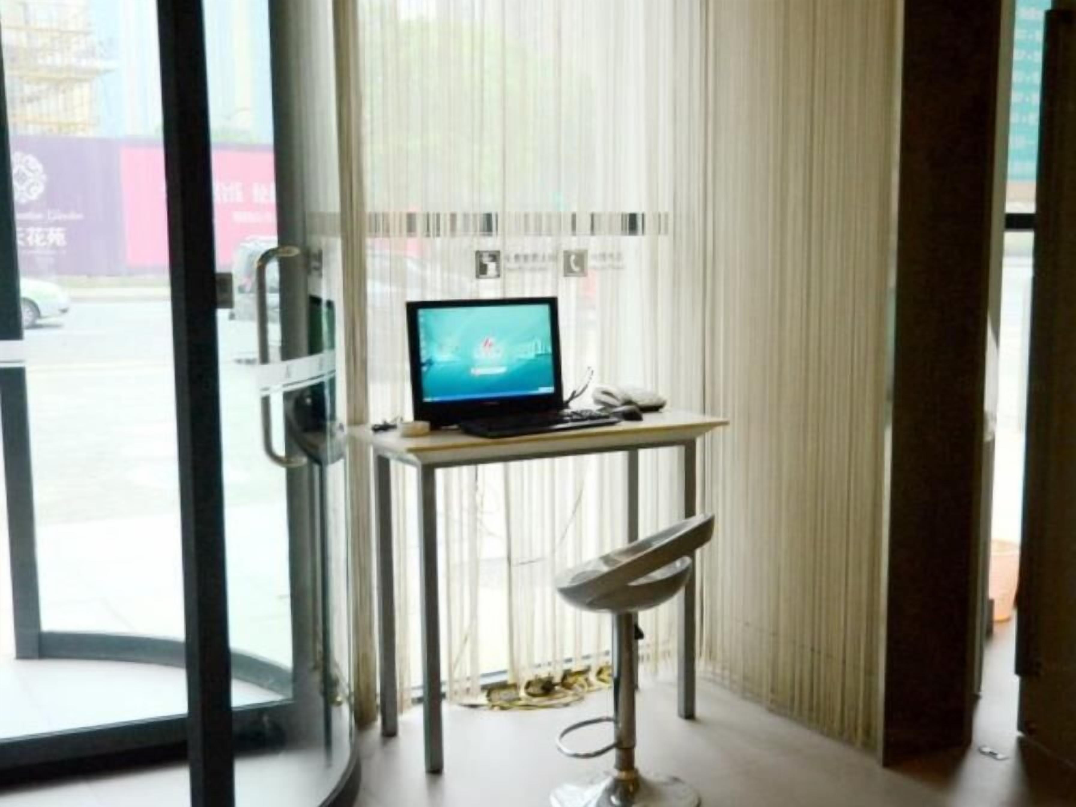 A room with a desk, a computer, a chair, and a view of the outside.