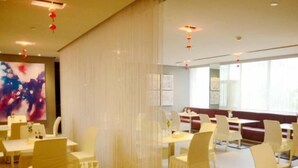 Un restaurant avec des chaises et des tables blanches, ainsi qu’une grande fenêtre.
