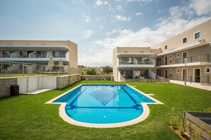 A modern residential building with a swimming pool surrounded by well-maintained grass and a stone wall. - Vantaris Blue - Adults Only (Apokoronas)