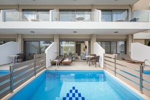 A modern indoor swimming pool with glass railings, lounge chairs, and a seating area with a view of the pool. - Vantaris Blue - Adults Only (Apokoronas)