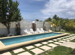 Una piscina al aire libre, sillones reclinables de piscina