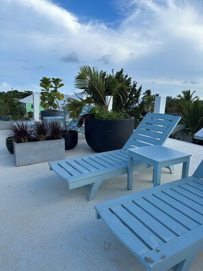 A beachside lounge area with blue lounge chairs and planters with various plants. - Sea Grape Studios (Providenciales)