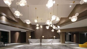 Een moderne lobby met een receptiebalie, marmeren vloeren en opvallende sferische hanglampen.