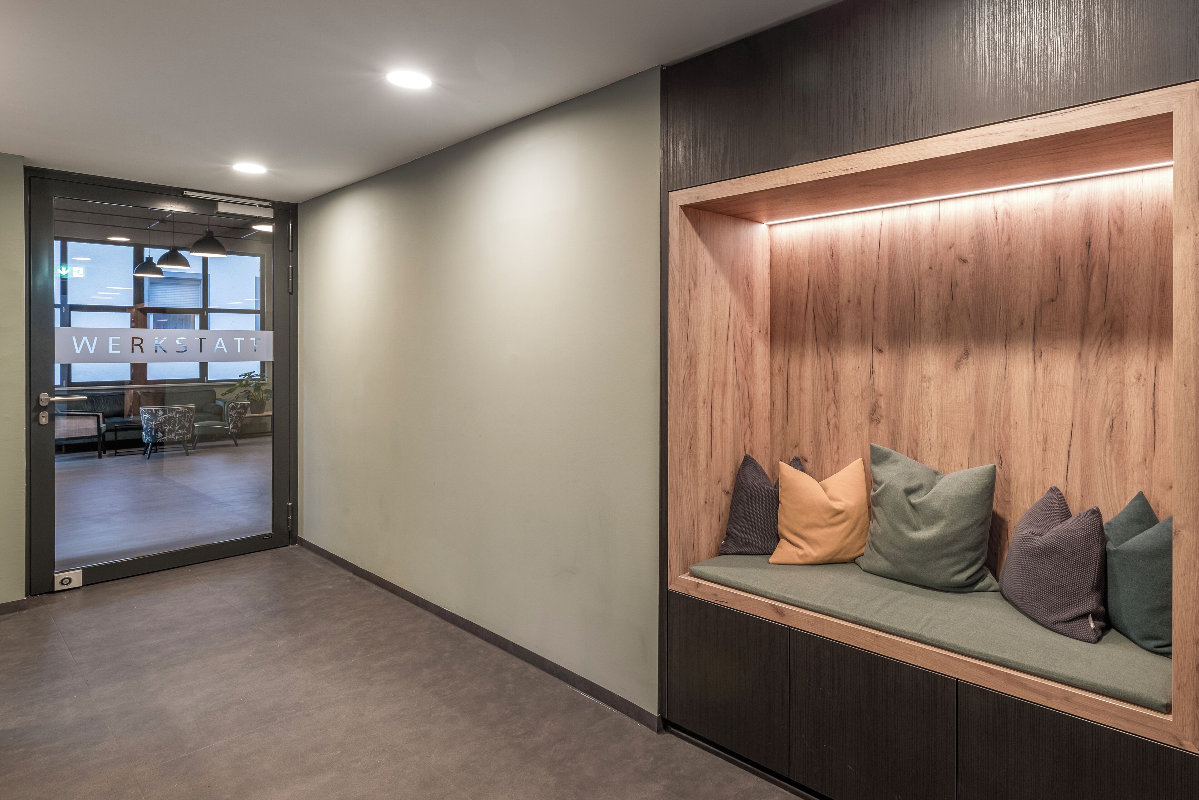 A modern waiting area with a bench, a reception desk, and a view into the office space.