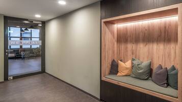 A modern waiting area with a bench, a reception desk, and a view into the office space.