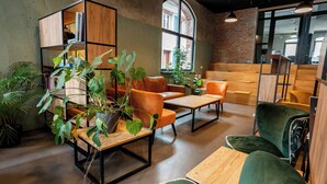 A modern interior with a wooden bookshelf, leather sofas, and green chairs. - Restaurant Hotel Zum Storchen (Waldkirch)