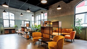 A spacious lounge area with modern furniture, large windows, and a variety of plants. - Restaurant Hotel Zum Storchen (Waldkirch)