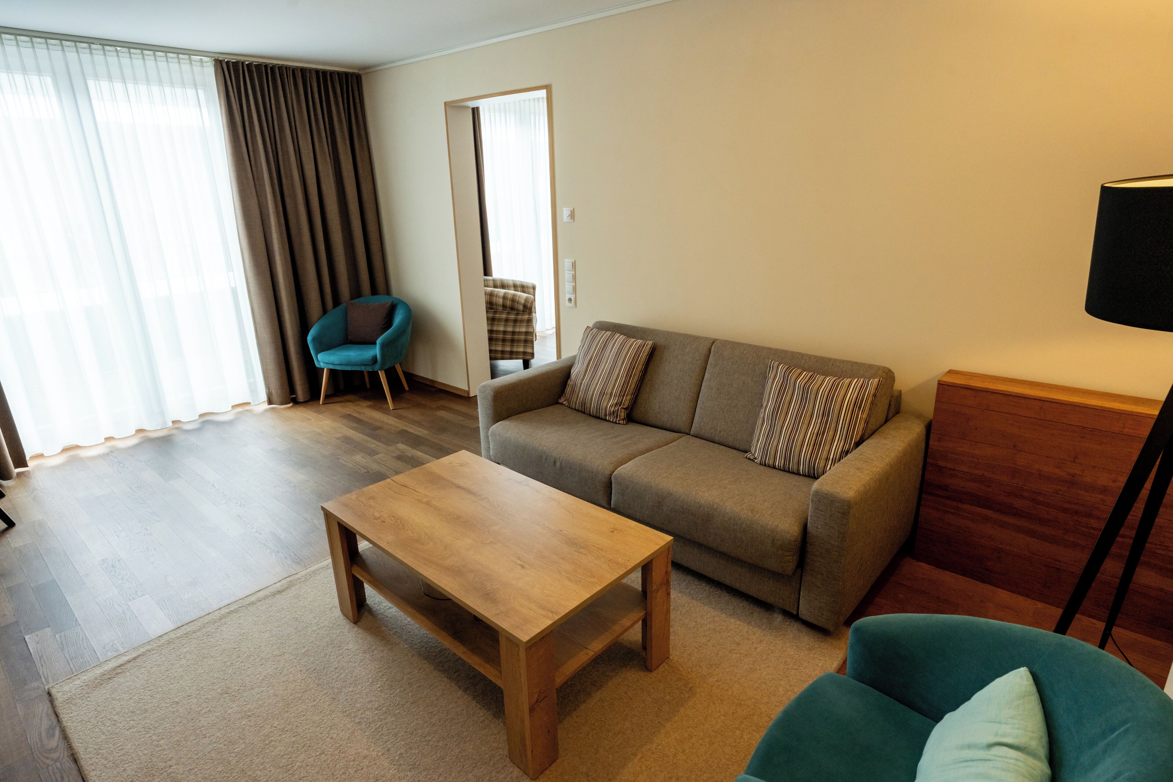 Ein Wohnzimmer mit einer Couch, einem Couchtisch, einem Sessel und einer Lampe.