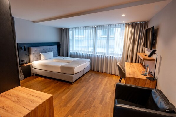 Una habitación de hotel moderna con una cama grande, un escritorio y una silla.