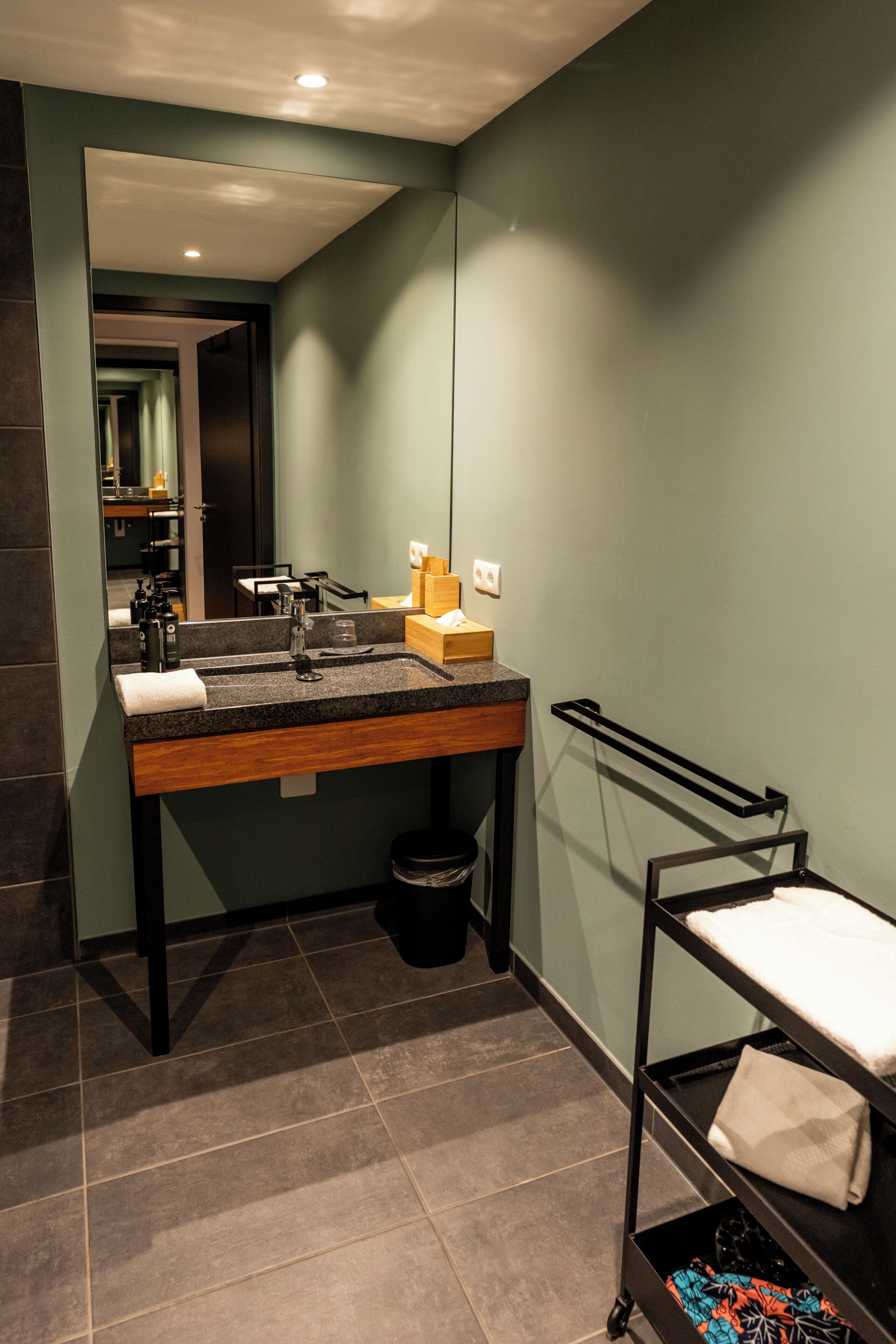 Ein modernes Badezimmer mit einer Granit-Arbeitsplatte, einem Waschbecken, einem Spiegel und einem Handtuchhalter.