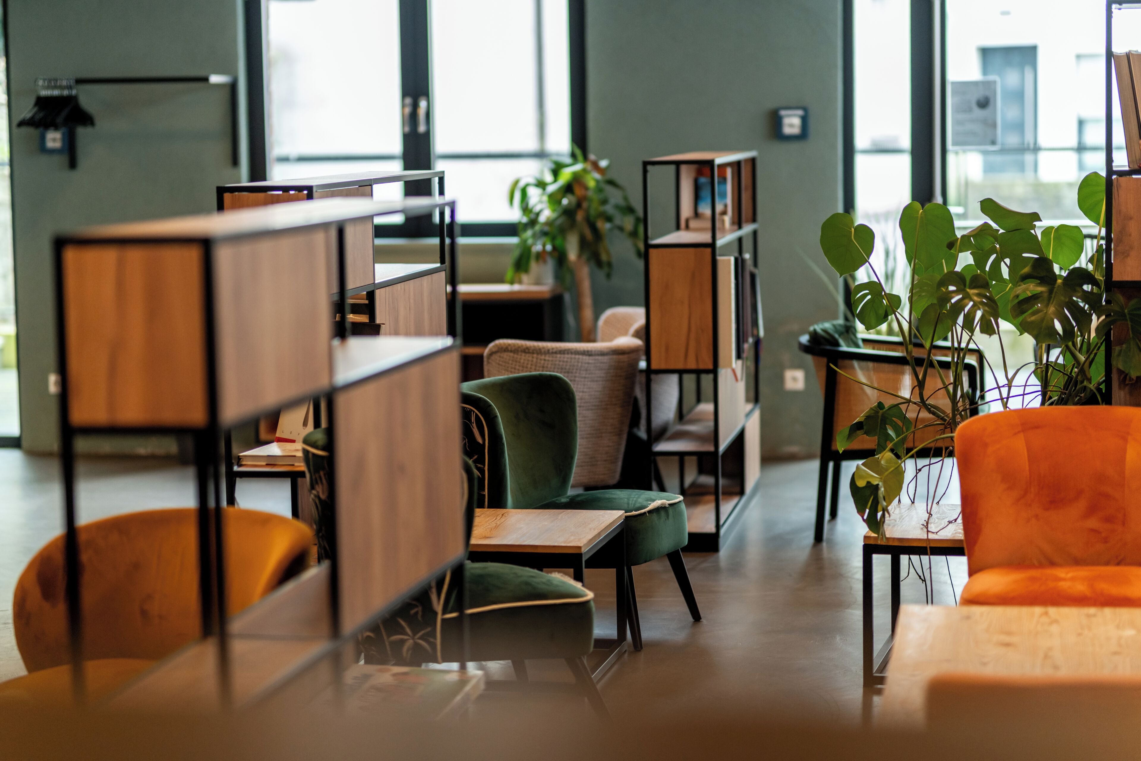 Un espace intérieur moderne, doté de meubles en bois, de chaises vertes et oranges, et de plantes en pot.