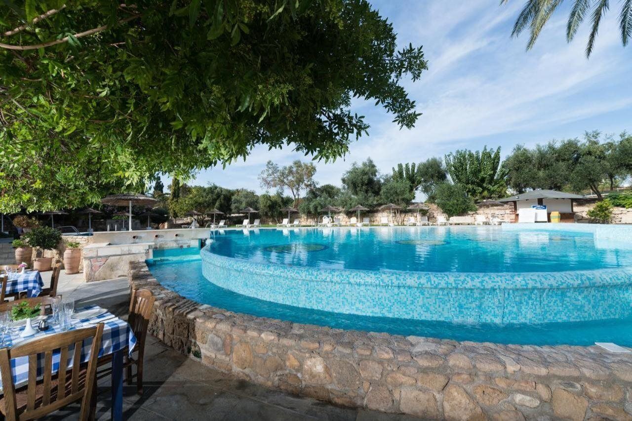 A swimming pool with a stone border, surrounded by outdoor seating and trees.