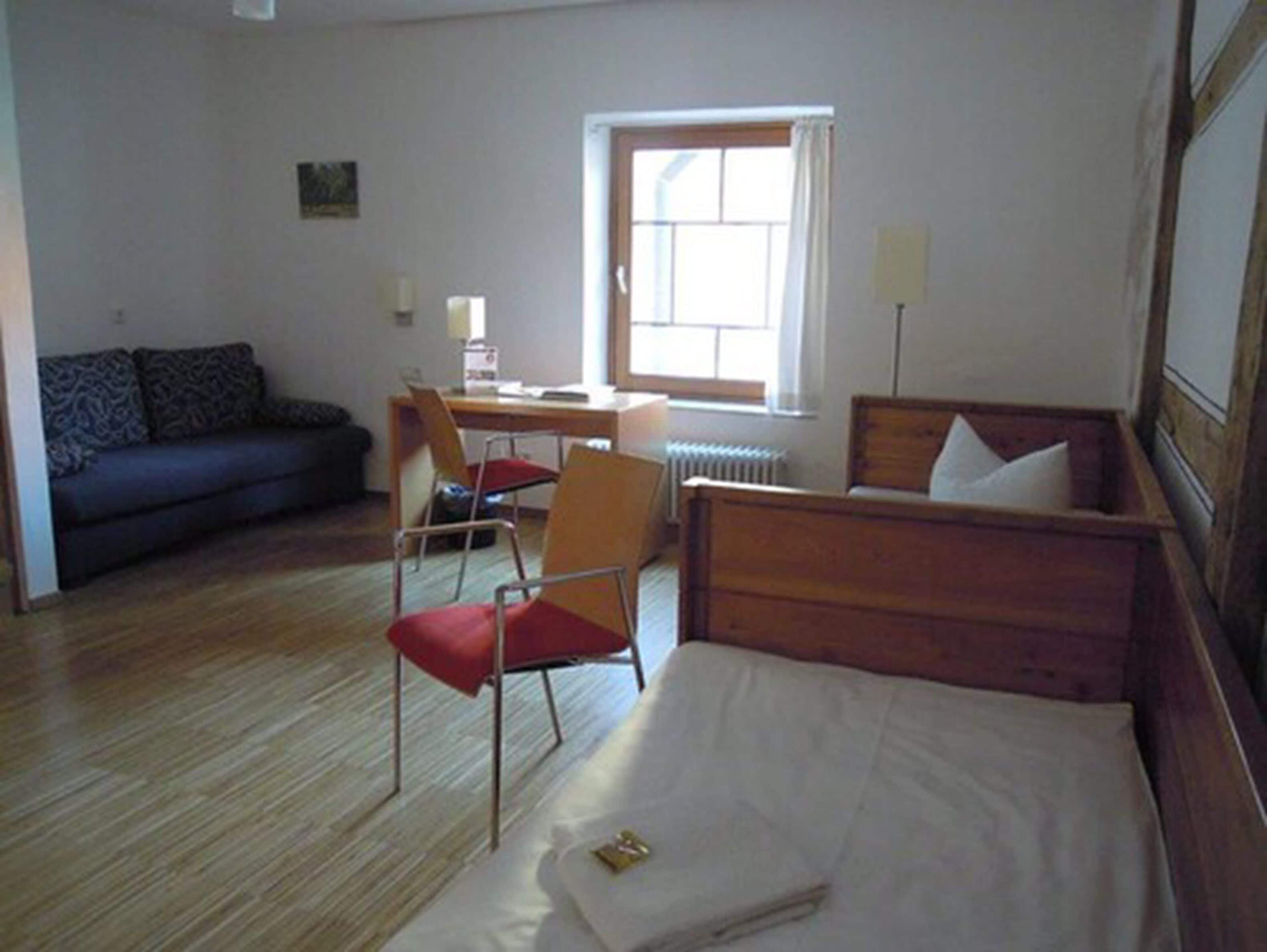 Una habitación con cama, escritorio, silla, sofá y ventana.