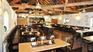 Ein geräumiges Restaurant mit Holzbalken, hohen Decken und verschiedenen Sitzgelegenheiten, darunter Tische und gemütliche Nischen.