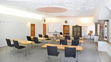 A conference room with tables and chairs, a whiteboard, and a decorative cabinet.