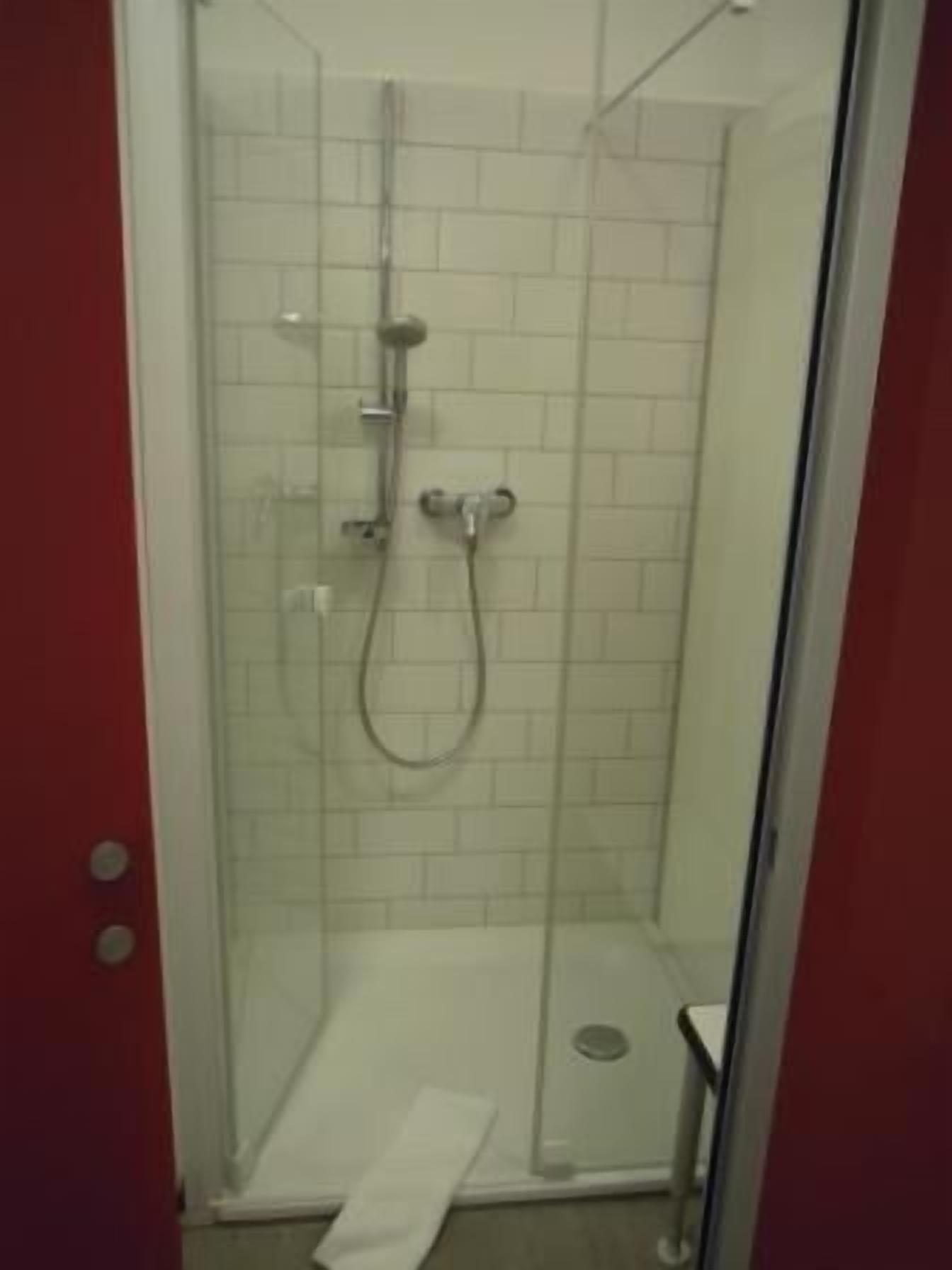 Un box de ducha con paredes de azulejos blancos y suelo blanco.
