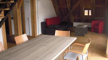 Un interior rústico de madera con una larga mesa de comedor, varias sillas, un sofá y una escalera.