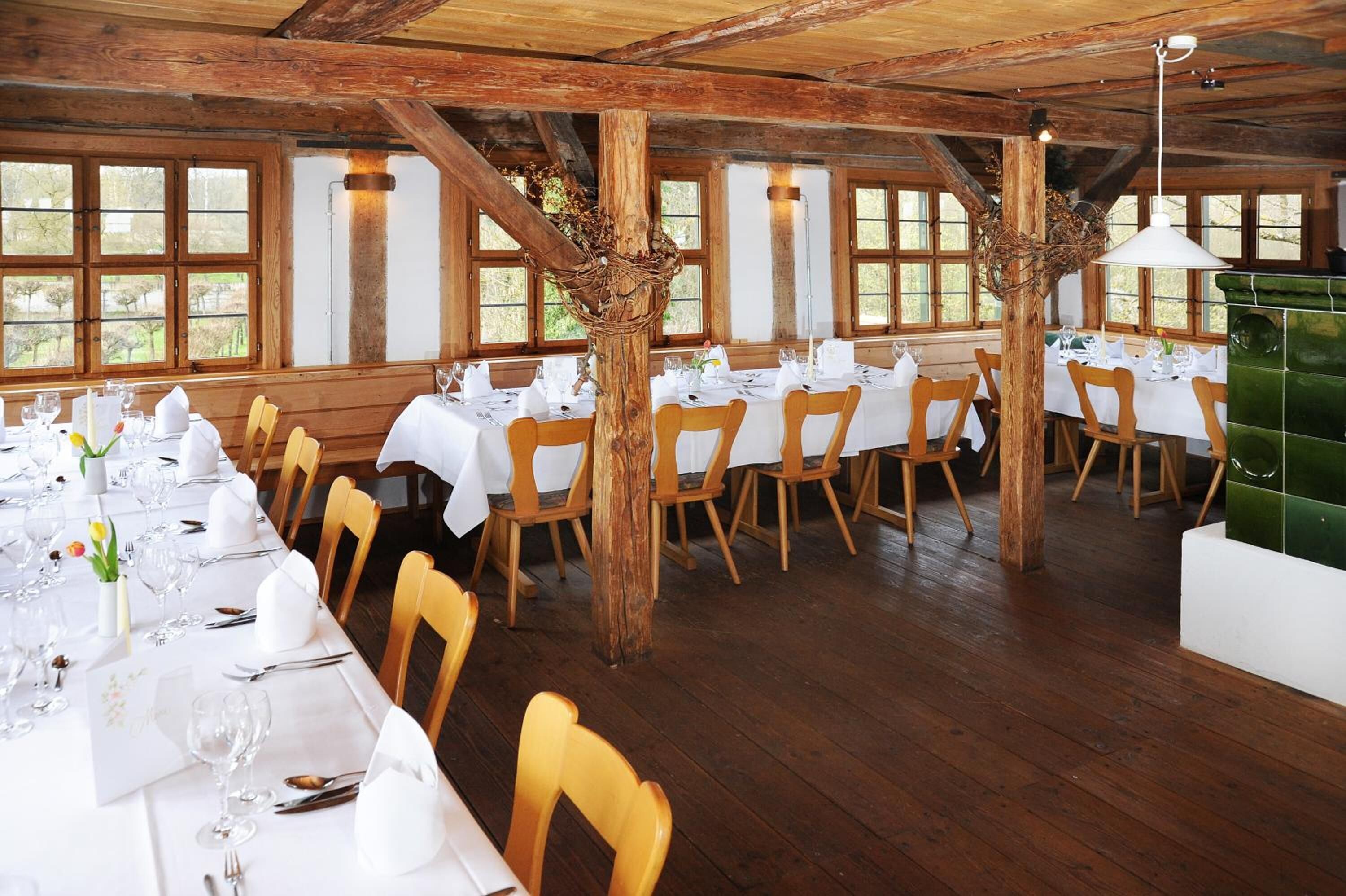 Een restaurant met houten balken, witte tafels en stoelen.